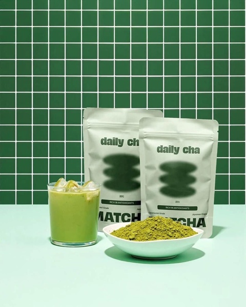 This creative showcases matcha powder in a minimalist, green-tiled setting, featuring the product packaging alongside a prepared iced drink to highlight utility.